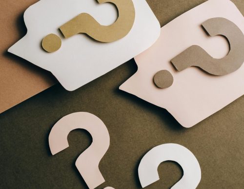Artistic paper cutouts of question marks creating a conceptual design on a brown surface.